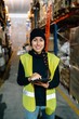 © Sergio Marcos/Stocksy - Smiling woman standing between racks in warehouse