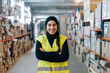 © Sergio Marcos/Stocksy - Smiling woman standing between racks in warehouse