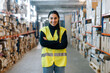 © Sergio Marcos/Stocksy - Smiling woman standing between racks in warehouse