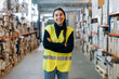© Sergio Marcos/Stocksy - Smiling woman standing between racks in warehouse