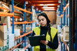 © Sergio Marcos/Stocksy - Young woman writing on clipboard in warehouse