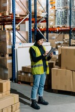 Serious Female Worker Using Tablet In Warehouse