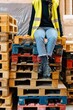© Sergio Marcos/Stocksy - Employee sitting on heap of pallets in warehouse