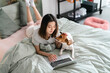 © Studio Marmellata/Stocksy - Happy woman lying with dog on bed