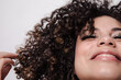 © Anna T Bailey/Stocksy - Model with curly hair and sparkly eyeshadows