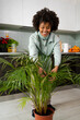 © Mauro Grigollo/Stocksy - Happy black woman caring for plants