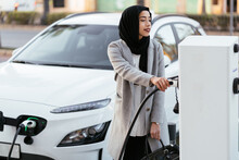 Muslim Woman Charging Electric Car On Station