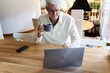 © Alba Vitta/Stocksy - Senior man having coffee cup and using laptop