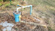 Blue PVC pipes of underground wells. Artesian well pumped from a submersible pump powered by photovoltaic power on a dirty concrete background with dry leaves in the countryside. Selective focus