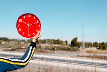 Man Holds A Red Clock, Nex Tot The Highway