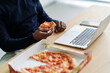 © Studio Marmellata/Stocksy - Remote worker eating pizza for lunch at workplace