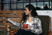 Young Woman Reading And Drinking Tea