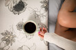 The slim legs of a shapely girl. She is holding a cup of hot coffee.