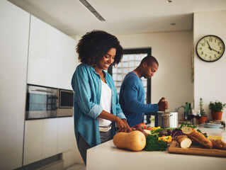Fototapete - Cooking together. Shot of a cheerful young couple preparing food together in the kitchen at home during the day.