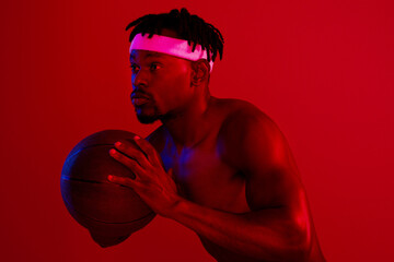 Poster - Im a beast out on the court. Red filtered shot of a young sportsman posing with a basketball in the studio.