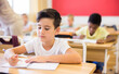 © JackF - Portrait of focused tween boy writing exercises in workbook in classroom during lesson in elementary school