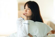 © amanaimages - ベッドの上で枕を抱く女性