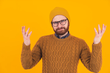 Portrait of young bearded Caucasian man in glasses and hat shrugging shoulders questioning gesture concept hipster isolated studio shot . High quality photo