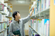 © amanaimages - 図書館で本を選ぶ男子学生