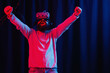 © endrews21 - an adult bearded man in a gray golf and virtual reality glasses in neon light on a dark background jumps and rejoices in victory