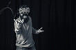 © endrews21 - a cheerful bearded man in gray golf and virtual reality glasses in neon light on a dark background raises his hands in joy of winning the game, black and white photo