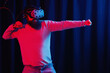 © endrews21 - bearded man in gray golf and virtual reality glasses in neon light on a dark background is studying karate