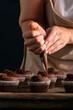 Chef fills the cupcakes with chocolate cream from the confectionery bag. Process of making muffins. Vertical frame.