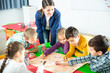 © JackF - Happy kids and female teacher playing together educational board game in classroom at elementary school