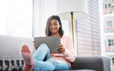 Sticker - On leave and loving it. Cropped shot of a beautiful young woman using a tablet while chilling on the sofa in the living room at home.