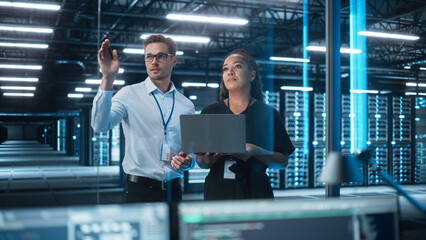 Factory Office Facility: Female Chief Engineer Holds Laptop Computer, Look Away and Brainstorming with Male Project Manager. Modern Industry Research and Development Center.