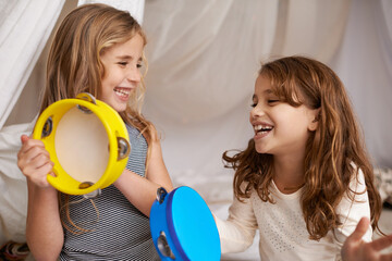 Poster - Music and joy. Shot of two cute little girls playing with tambourines at home.