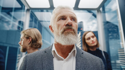 Wall Mural - Portrait of a Confident Middle Aged Successful Businessman Riding in Crowded Glass Elevator in a Modern Business Center. Senior Manager on the Way to Office in a Lift.