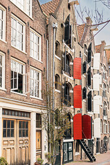 Row tall old brick canal houses and a street in Amsterdam. Famous scenic view. City of bicycles.