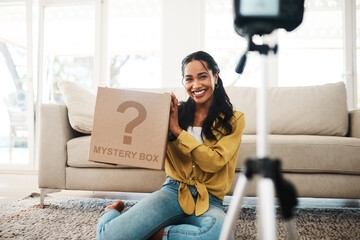 Wall Mural - We got new mail. Cropped shot of an attractive young businesswoman sitting in her living room and holding up a mystery box while vlogging.