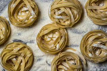 Wall Mural - Pasta nests on flour on a black background. Shape of pasta. traditional cooking