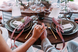 Fototapeta Miasto - Frisch verheiratetes Paar sitzt am Tisch Hand in Hand beim Abendessen in Rosa