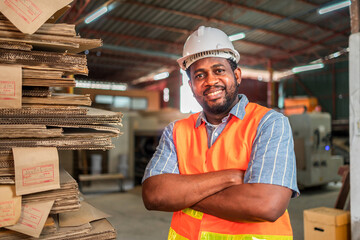 Happy male factory manager using digital tablet in warehouse while standing against goods shelf looking at camera.Products and corrugated cardboard. Small business factory concept.