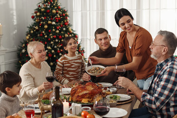 Poster - Woman with bowl of traditional Christmas kutia and her family during festive dinner at home. Slavic dish