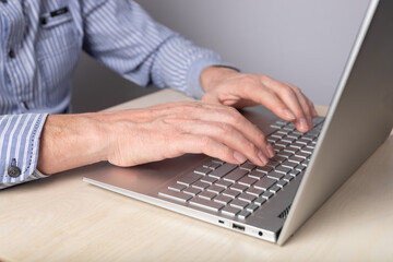 Poster - Man hands closeup typing on laptop keyboard. Man sitting at table with computer and working remotely, studying online, surfing Internet. High quality photo