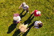 © New Africa - Top aerial view of people standing in circle on green grass. Drone photography