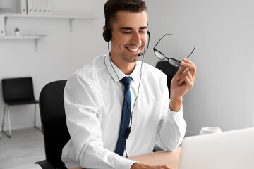 Poster - Male consultant of call center with eyeglasses using laptop in office