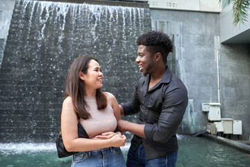 Smiling friends of different ethnicities standing and talking in a shopping mall