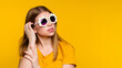 Close up portrait girl in basic bright yellow wear in stylish sunglasses with daisies against yellow wall. Nice young woman looks away and dreams. Concept arrival spring. Copy space