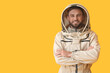 Male beekeeper in protective suit on yellow background