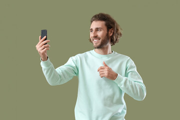 Canvas Print - Handsome man with mobile phone taking selfie on green background