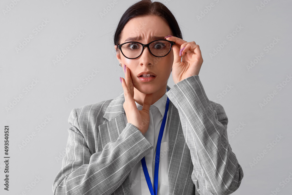 Worried young businesswoman on grey background
