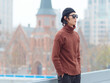 Portrait of handsome Chinese young man with sunglasses standing with hands in pocket with Shanghai city landmarks background, male fashion, cool Asian young man lifestyle.