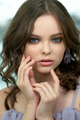 Wall Mural - Pretty teen girl with curly hair smiles and looks to the camera. Portrait of beautiful young teenager little girl with nice hairstyle. Close-up, selective focus