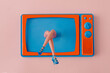 © Miss V - Women's legs with blue high heels shoes coming out of a retro old blue and orange tv against peach background. Creative concept for vintage fashion. Design for entertainment and technology banner.