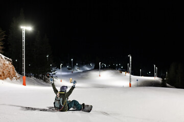 Wall Mural - Snowboarder girl posing on slopes. Night skiing in winter resort..